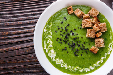 broccoli spinach cream soup on rustic wooden background
