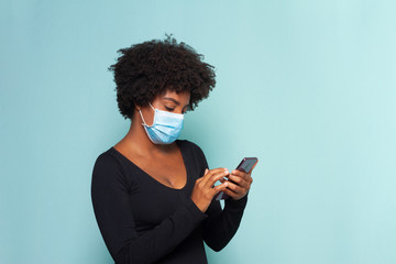 black muher with black power hair wearing protective mask with smartphone in hands