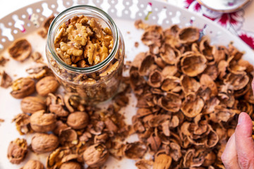 Whole walnuts in a jar. Walnuts on a white cutting board