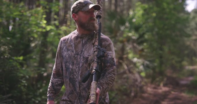 Walking through woods hunting with rifle
