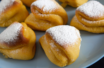 Several triangular buns on a blue plate close-up view from the side.