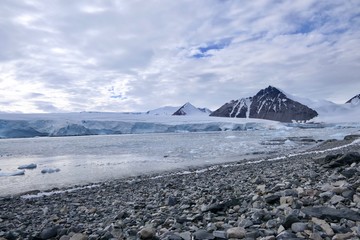 Glacier front with mountain and stone beach landscape in Antarctica, Stonington Island