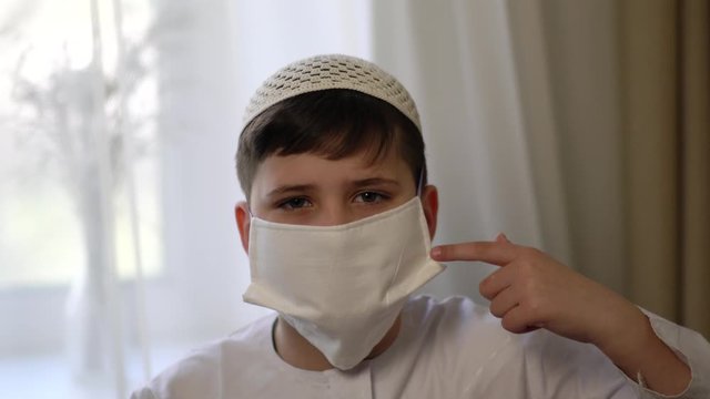 Muslim boy wearing surgical mask. Covid-19 and coronavirus concept. Black background and negative space.
