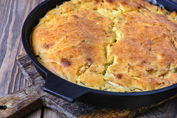 Freshly baked pie ready for dinner, hot pie stuffed in a cast iron pan on a wooden board, closeup