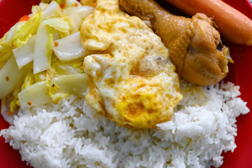 fast food of steamed chicken leg and sausage and fried egg and cabbage and rice