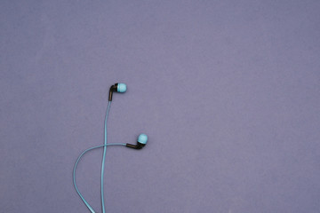 Thin blue headphones on a blue background. Space for text. Isolated