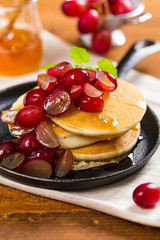 Healthy Homemade Classic American Pancakes with Sliced Red Grapes and Maple Syrup Close Up. Selective focus.