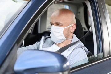 Man driving a car in medical protective mask.