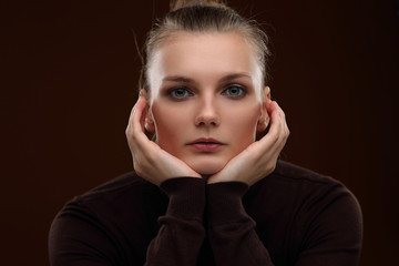 Beautiful girl in a maroon turtleneck on a brown background