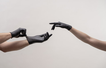 Obraz premium Male and female hand in black gloves stretch to touch each other.