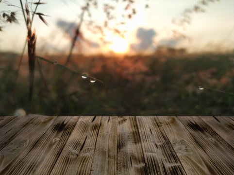 Old wooden teble with the blur background. The background is the flowers and golden shining sunrise blurred.