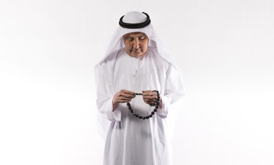 studio portrait of an old Arab man in white clothes on a white background