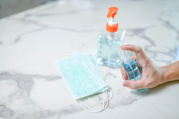 Image of a hand of a man with a bottle of alcohol washing hands, jel and mask .Stop and staying safe from COVID-19