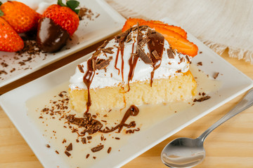 Three milk cake with chocolate syrup and some strawberries