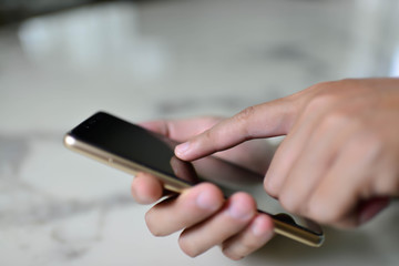 Close-up image of male hands using smartphone on the table