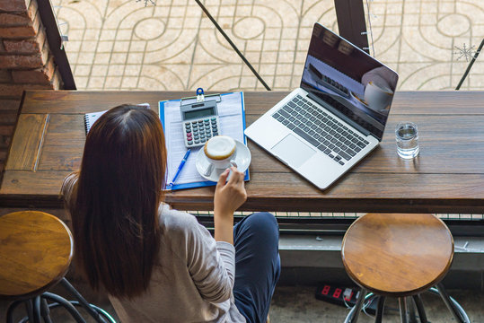 Asian freelancer drinking hot cup of coffee at the rustic cafe - Powered by Adobe