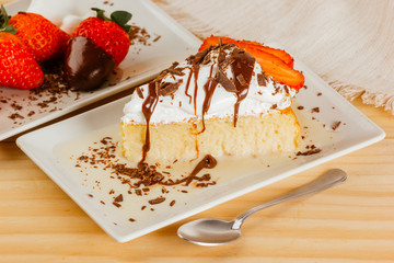 Three milk cake with chocolate syrup and some strawberries