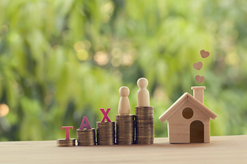 Small wooden house and heart, family members, words tax, on rows of rising coins on table. Family...