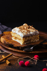 Piece of cake three milk prepared at home. The image is made on a dark background and rustic boards. Latin American dessert