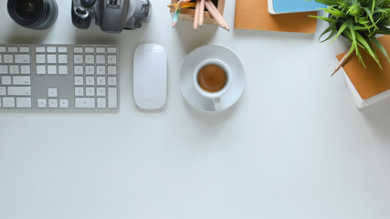Top view image of hot coffee cup putting on white working desk and surrounded by wireless mouse,...