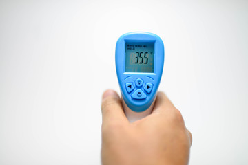 Hand holding Digital Infrared Thermometer (thermometer gun) for check forehead temperature measurement scan from Coronavirus Disease 2019 (COVID-19)