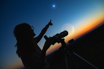 Fototapeta premium Silhouette of a woman and telescope with twilight sky.