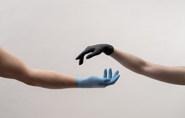 Male and female hand in black gloves stretch to touch each other.