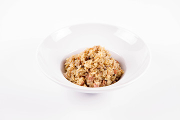 Risotto with button mushroom and bacon on a plate on a white background