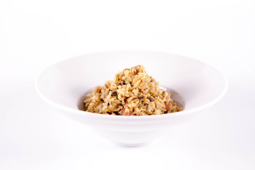 Risotto with button mushroom and bacon on a plate on a white background