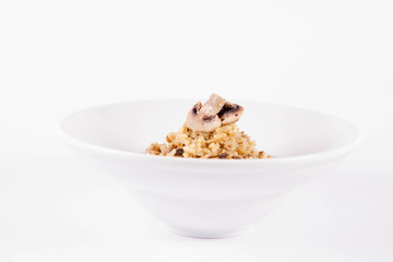 Risotto with button mushroom and bacon decorated with mushroom on a plate on a white background