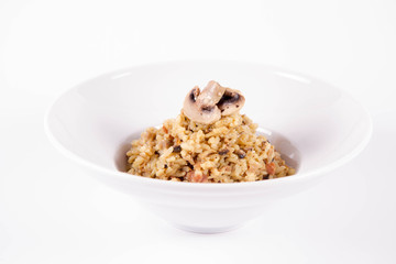 Risotto with button mushroom and bacon decorated with mushroom on a plate on a white background