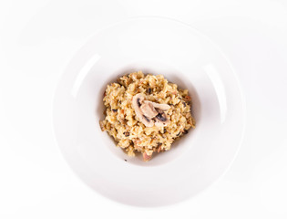 Risotto with button mushroom and bacon decorated with mushroom on a plate on a white background