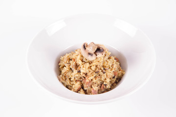Risotto with button mushroom and bacon decorated with mushroom on a plate on a white background