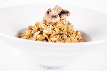 Risotto with button mushroom and bacon decorated with mushroom on a plate on a white background