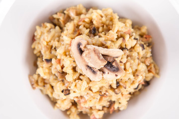 Risotto with button mushroom and bacon decorated with mushroom on a plate on a white background