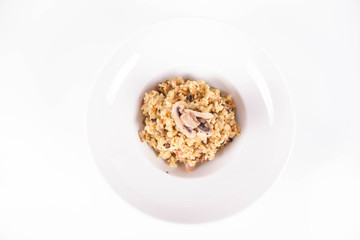 Risotto with button mushroom and bacon decorated with mushroom on a plate on a white background