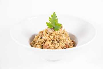 Risotto with button mushroom and bacon decorated with parsley on a plate on a white background