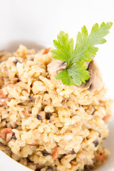 Risotto with button mushroom and bacon decorated with parsley on a plate on a white background