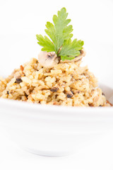 Risotto with button mushroom and bacon decorated with parsley on a plate on a white background