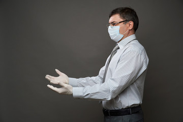 man dressed as a businessman looking on his palms, posing in studio on gray background