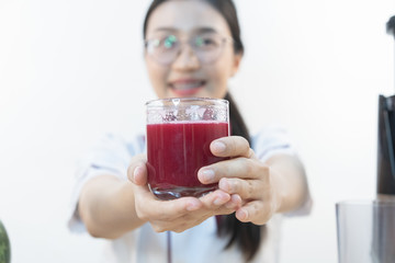 A cute girl makes vegetable juice, with carrot apple orange cranberry beetroot and mango in chef suit.