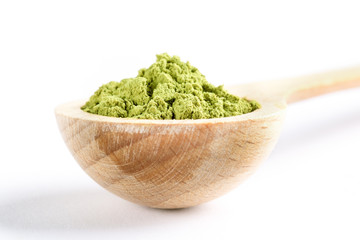 Close-up wooden spoon with green japanese matcha tea powder on white background. Selective focus, copy space.