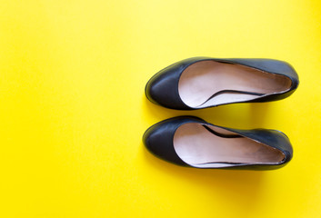 pair of black female shoes with toes on yellow background. free copy space. Overhead shot of elegant shoes. Top view, flat lay. Concept of fashion. Summer