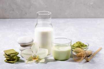 Glass of matcha latte tea with set for its preparation, green chocolate with matcha, spa stones,...