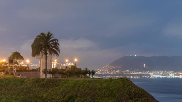 Intihuatana park with panoramic view of Miraflores district and Morro Solar hill on a background day to night timelapse, in Lima, Peru. Palm and caffee with illuminated street lights