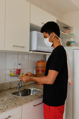 Man adult black wearing coronavirus  mask  washing dishe in kitchen