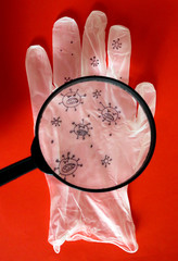 Magnifying glass and glove with a virus drawing. Disposable gloves are recommended for personal protection against Coronavirus, COVID-19 infection. Medical symbol of hygiene and prevention concept.