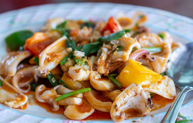 Stir fried squid with salted egg. Delicious Asian cuisine stir fried squid with salted egg in white plate.