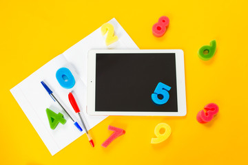 school paint supplies and tablet on a yellow isolated background, theme back to school