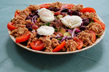 A nicoise salad with canned tuna, anchovies, tomatoes, potatoes and vegetable
